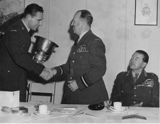 Photo: RCAF Flyer Team Manager S/L Sandy Watson presents the World Amateur Hockey Cup to Air Marshall Wilf Curtis, chief of air staff.