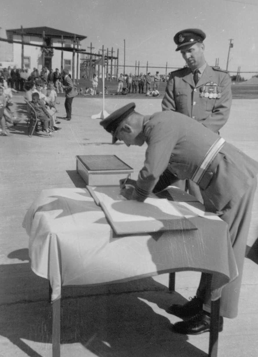 Photo: W/C Hubert Brooks completes signature of transfer of command document for RCAF Moisie 